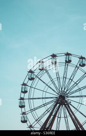 Une grande roue ronde à une foire amusante dans un ciel bleu clair Banque D'Images