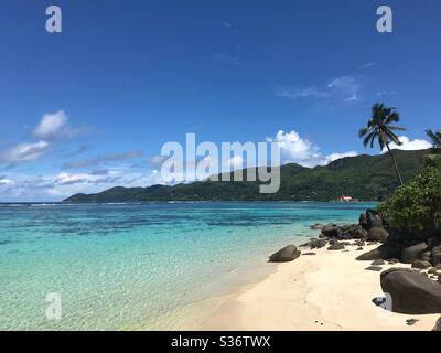 Plage tropicale à la Digue, Seychelles avec sable blanc, palmiers, eau turquoise et rochers de granit Banque D'Images