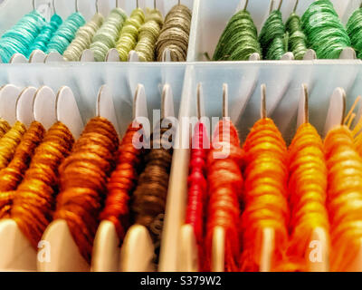 Une collection artistique, un arc-en-ciel de fils de broderie colorés sur des bobines en carton organisées dans une boîte Banque D'Images