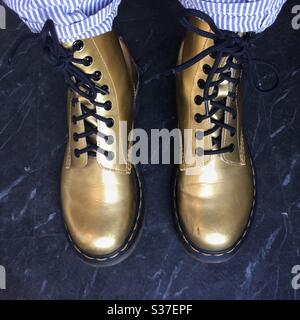 Une femme portant une paire de bottes Doc Martens d'or, vue d'en haut en regardant vers le bas Banque D'Images