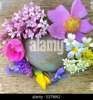 Fleurs entourant l'orthographe de roche amour Banque D'Images