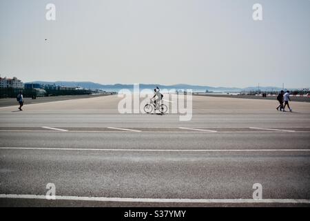 Cycliste traversant la piste à Gibraltar le matin en soirée Banque D'Images