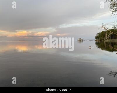 Coucher de soleil coloré sur une baie calme avec bateau et héron debout dans l'eau Banque D'Images