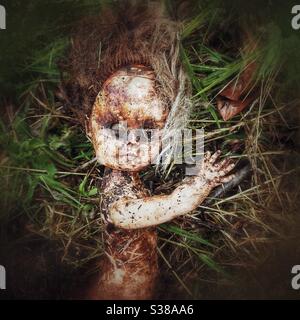 Photographie d’une poupée d’enfant créepy jetée dans une longue herbe. Banque D'Images