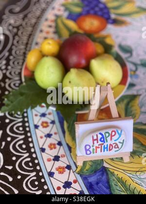 Joyeux anniversaire célébré avec des fruits bio frais de saison et une pierre colorée sur une table colorée Banque D'Images