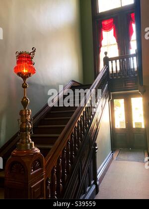 Une lampe en verre sur le poste de newel d'une banister dans une maison de style Reine Anne. Banque D'Images