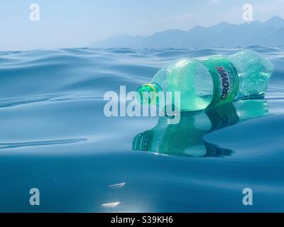 Bouteille en plastique vert flottant sur une mer bleue Banque D'Images