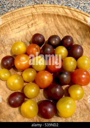 Une variété de tomates en fleur colorées dans un bol en bois. Banque D'Images