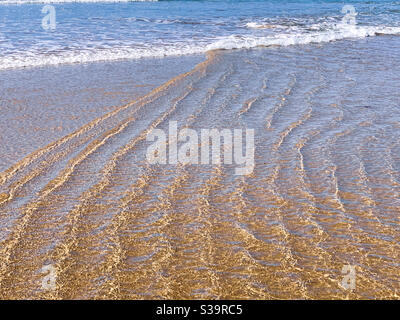 Motif dans le sable humide de plage fait par l'eau de l'océan et les vagues, frogné aux bords, les lignes et les ondulations Banque D'Images