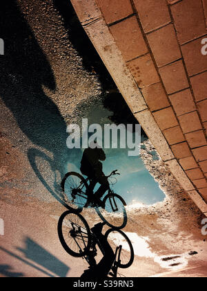 Ombre, silhouette et reflet du cycliste sur la route. Banque D'Images