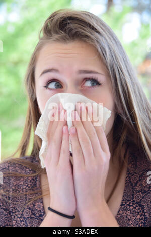 Saison de la grippe, jeune femme éternuant dans le mouchoir