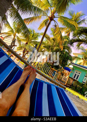 Vue d'une femme qui se détend sur un hamac et qui regarde vers la plage et les palmiers à Key Largo, Floride. Banque D'Images