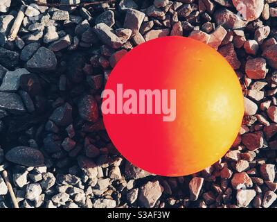 Boule en plastique orange sur pierre de gravier Banque D'Images