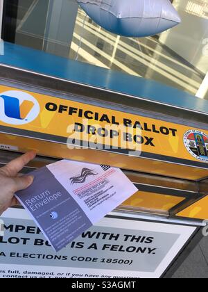 Une main déposant un bulletin de vote par la poste dans une boîte de vote officielle du comté de Los Angeles lors de l'élection de novembre 2020. Banque D'Images