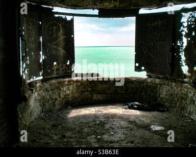 Vue sur la mer depuis le refuge de guerre avec porte en métal rouillé et graffitis Banque D'Images