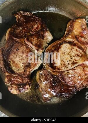 Deux steaks de bœuf brunissent dans une poêle Banque D'Images