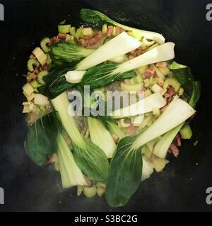 Cuisson du bok Choy, du céleri et du bacon dans une casserole Banque D'Images