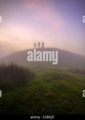 Trois figures silhouetées au sommet de la montagne Garth au crépuscule, dans une soirée brumeuse de la fin novembre. Cardiff, pays de Galles du Sud. Banque D'Images