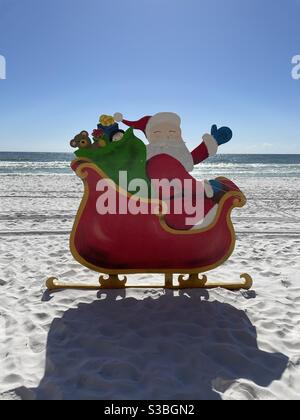 Santa dans un traîneau rouge avec des cadeaux sur le sable blanc plage avec vue sur l'océan Banque D'Images