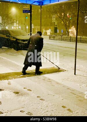 Solo Night porter élimine la neige du trottoir au 30 Park Avenue lorsqu'une tempête de neige commence à New York. Banque D'Images