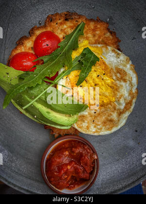 Petit-déjeuner composé d'œufs, d'avocats et de rösti. Banque D'Images