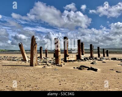 Vieux poteaux en bois abîmés sur la plage de Crowpoint, sur la côte nord du Devon, en Angleterre, avec des nuages spectaculaires par une journée d'été venteuse Banque D'Images