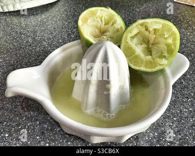 Limes les moitiés reposant sur un presse-fruits avec le citron vert Jus pressé Banque D'Images