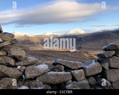 Écart dans le mur sur le trek Slieve Binnian, regardant sur la vallée d'Annalong vers un slieve Donard enneigé. Banque D'Images