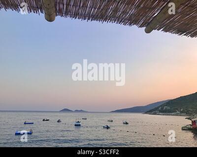 Vue sur la mer Méditerranée au coucher du soleil avec de petits bateaux un restaurant au bord de la plage Banque D'Images