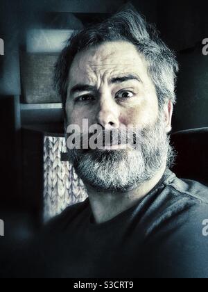 Portrait d'homme barbu perplexe avec éclairage moody Banque D'Images