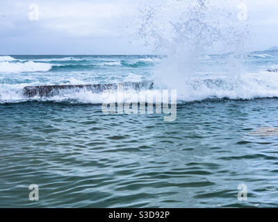 Vagues qui explosent au-dessus du bord de la piscine de roche, créant une éclaboussure géante. Horizon et Océan Pacifique en arrière-plan Banque D'Images