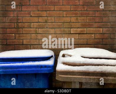 Les poubelles intérieures sont recouvertes de neige contre un mur de briques. Espace pour la copie Banque D'Images