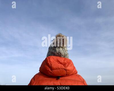 Vue arrière d'une femme à l'extérieur, portant un hiver chaud manteau et bonnet de galet en laine avec ciel bleu et copier l'espace Banque D'Images