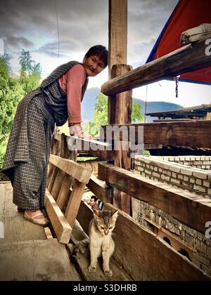 Femme bhoutanaise en robe traditionnelle de kira et son chat, Bhoutan Banque D'Images