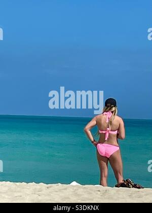 Une femme blonde vêtue de bikini sur Miami Beach regarde l'océan turquoise et le ciel bleu clair lors d'une journée de plage parfaite en février, Floride, États-Unis Banque D'Images