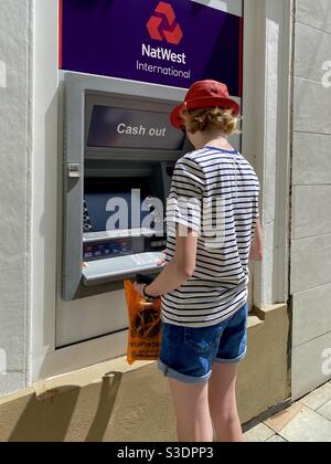 Adolescent utilisant un distributeur de billets international natwest Banque D'Images