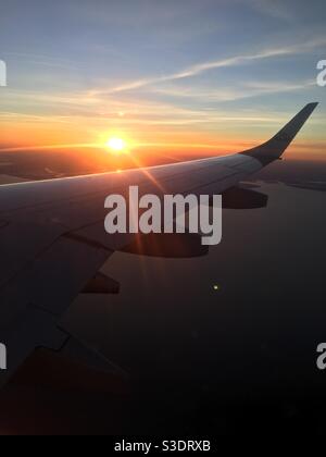 Plan coucher de soleil de la fenêtre d'un avion passager et en montrant le soleil qui s'embrase au-dessus de l'aile Banque D'Images