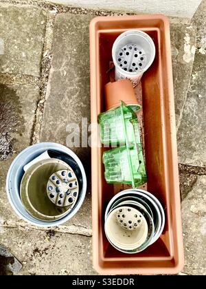 Une collection de pots vides de plantes en plastique pour les graines dans un jardin sur un patio Banque D'Images