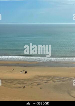 Cavaliers et marcheurs sur Three Cliffs Bay, Gower, pays de Galles du Sud, marée basse, mars. Banque D'Images