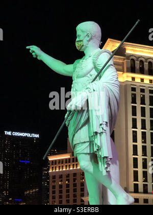 Las Vegas, USA. 11th April, 2021. Late at night on the Vegas strip a Roman Statue at Caesars Palace wearing a Covid mask.. Stock Photo