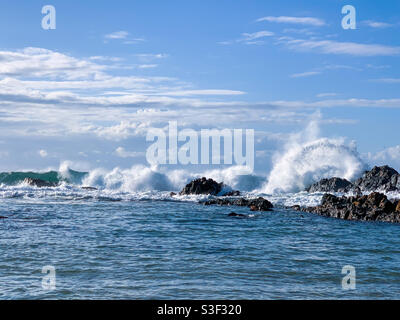 Belle journée de ciel bleu à la plage, une arche d'eau blanche en mousse provenant de vagues qui s'écrasant sur des rochers près du rivage. Projection de jets de mer. Sawtell Australie Banque D'Images