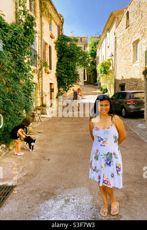 Femme philippine asiatique posant dans une petite rue pavée de village, et sa petite fille de Philippine asiatique mixte jouant avec un chat noir et blanc, près de Montpellier, Occitanie, au sud de la France Banque D'Images