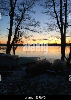 Une vue fraîche en début de printemps en soirée avec des bateaux et des arbres Silhouettes au premier plan et coucher de soleil sur Arabianranta la mer Banque D'Images