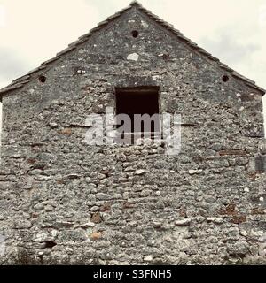 Détails architecturaux sur l'extrémité pignon d'une ancienne ferme en pierre avec fenêtre. Ancienne grange en pierre Banque D'Images