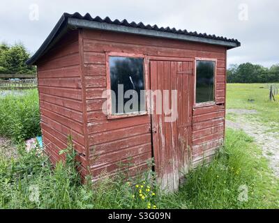 Ancien hangar en bois rouge dans un champ Banque D'Images