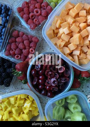Mélange de fruits dans des récipients séparés. Cantaloup, cerises, mangue, kiwi, framboises, fraises, bleuets, raisins. Banque D'Images