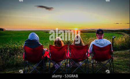 Famille de quatre personnes regardant le coucher de soleil sur Islay depuis Machrihanish à Kintyre, en Écosse Banque D'Images