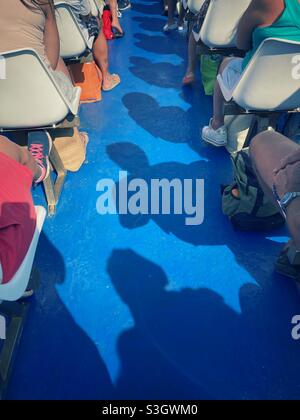 Les passagers et leurs ombres assis en rangées sur un navire à passagers voyageant vers les îles Tremiti sur la mer Adriatique, Italie Banque D'Images