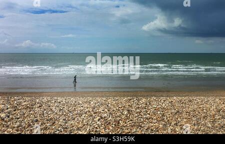 Marcheurs sur la plage de galets à Bracklesham Bay, West Sussex Banque D'Images