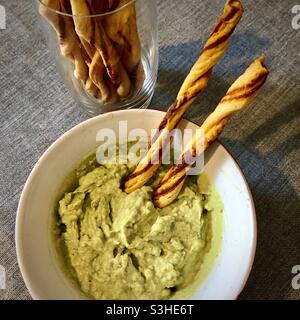 Trempette d'avocat maison dans un bol avec gressins commerciaux. Banque D'Images